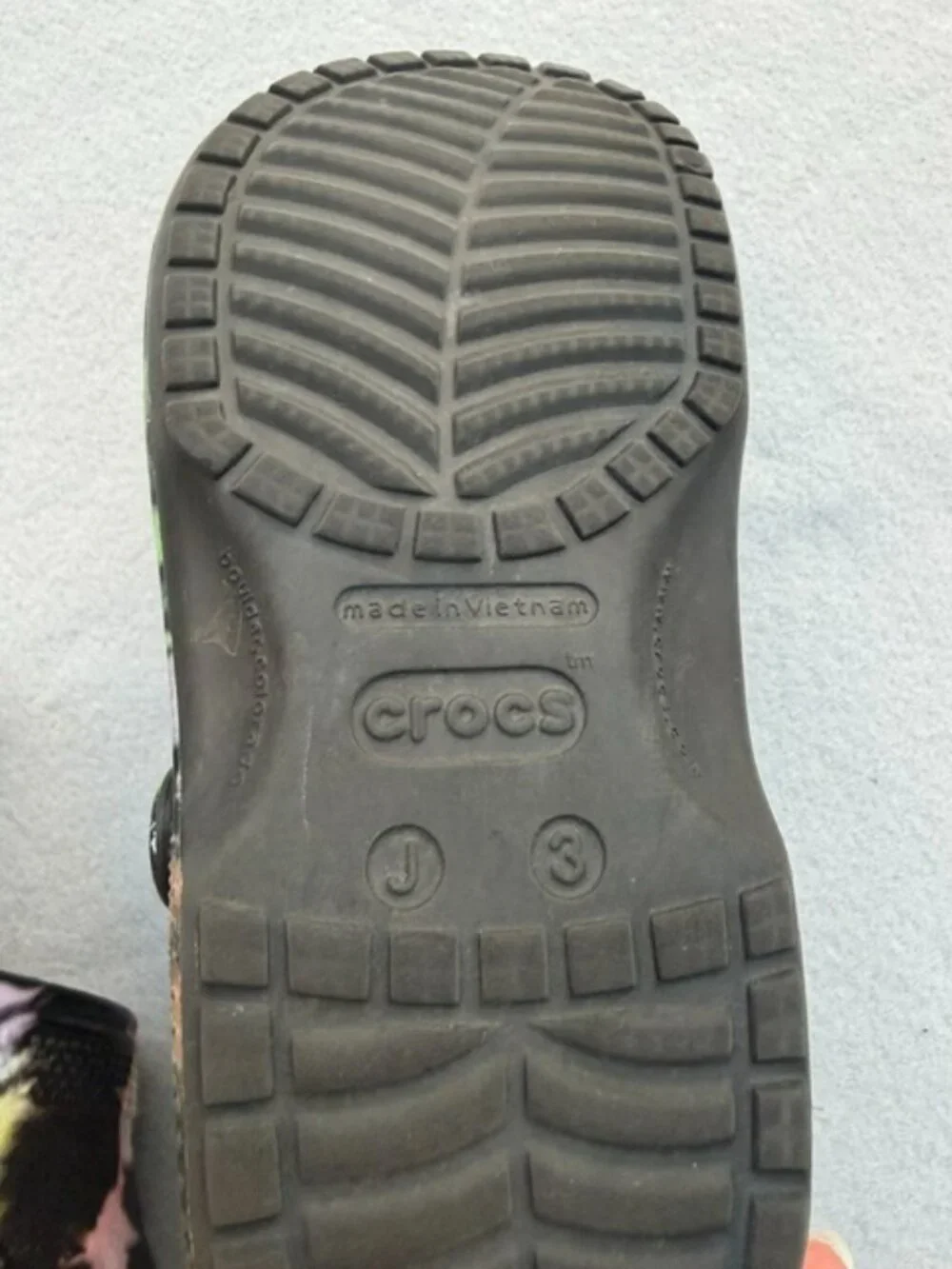 The product is a pair of Crocs Kids Size J 3 Black Tie-Dye Classic Clog Sandals